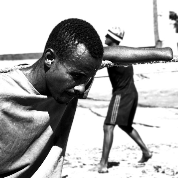 Fotografía documental blanco y negro primer plano pescador sin una mano tirando de cuerda pesada, expresión de esfuerzo, costa colombiana
