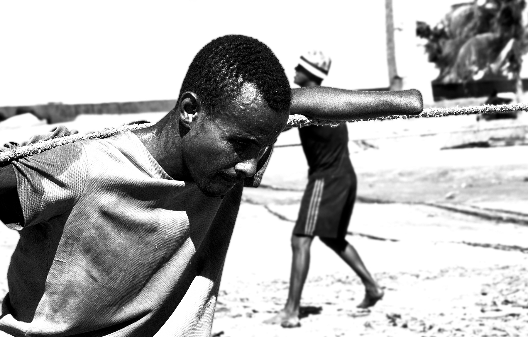 Fotografía documental blanco y negro primer plano pescador sin una mano tirando de cuerda pesada, expresión de esfuerzo, costa colombiana