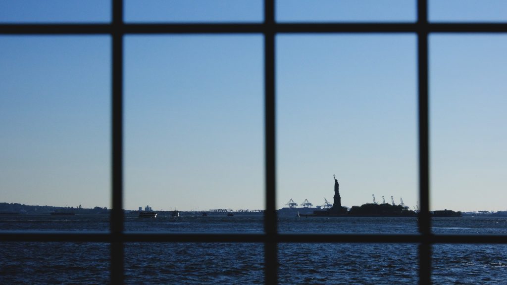 Fotografía artística conceptual Estatua de la Libertad Nueva York, vista a través de rejas, "Land of FREEDOM", silueta distante
