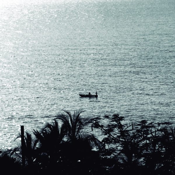 Fotografía artística blanco y negro pescadores bote contraluz mar brillante, palmeras silueta, costa tropical.