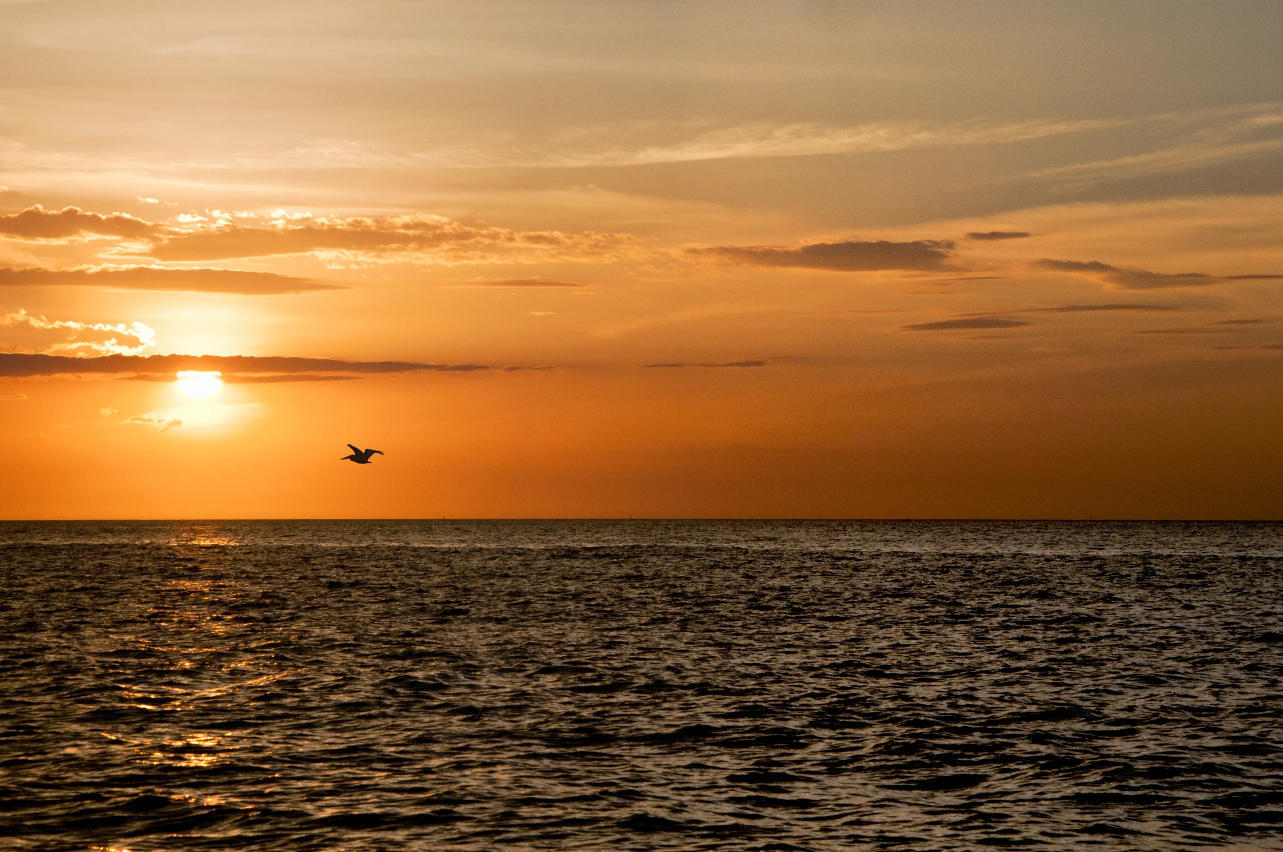 sol poniéndose sobre el mar con pequeña embarcación