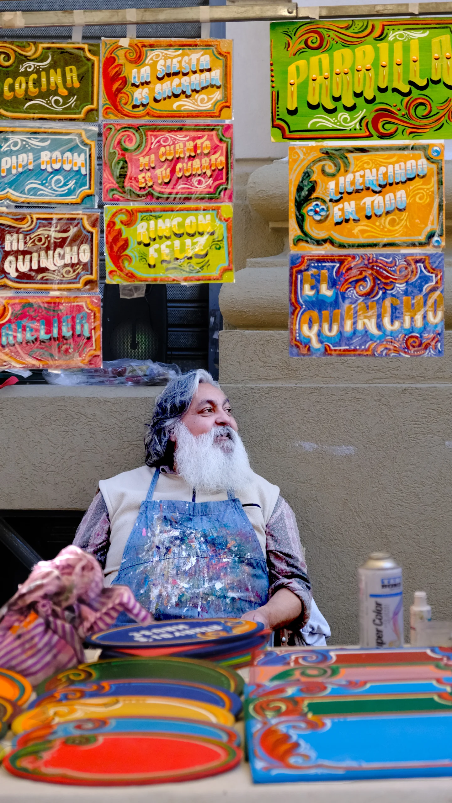 pintor rodeado de letreros pintados a mano en espacio urbano