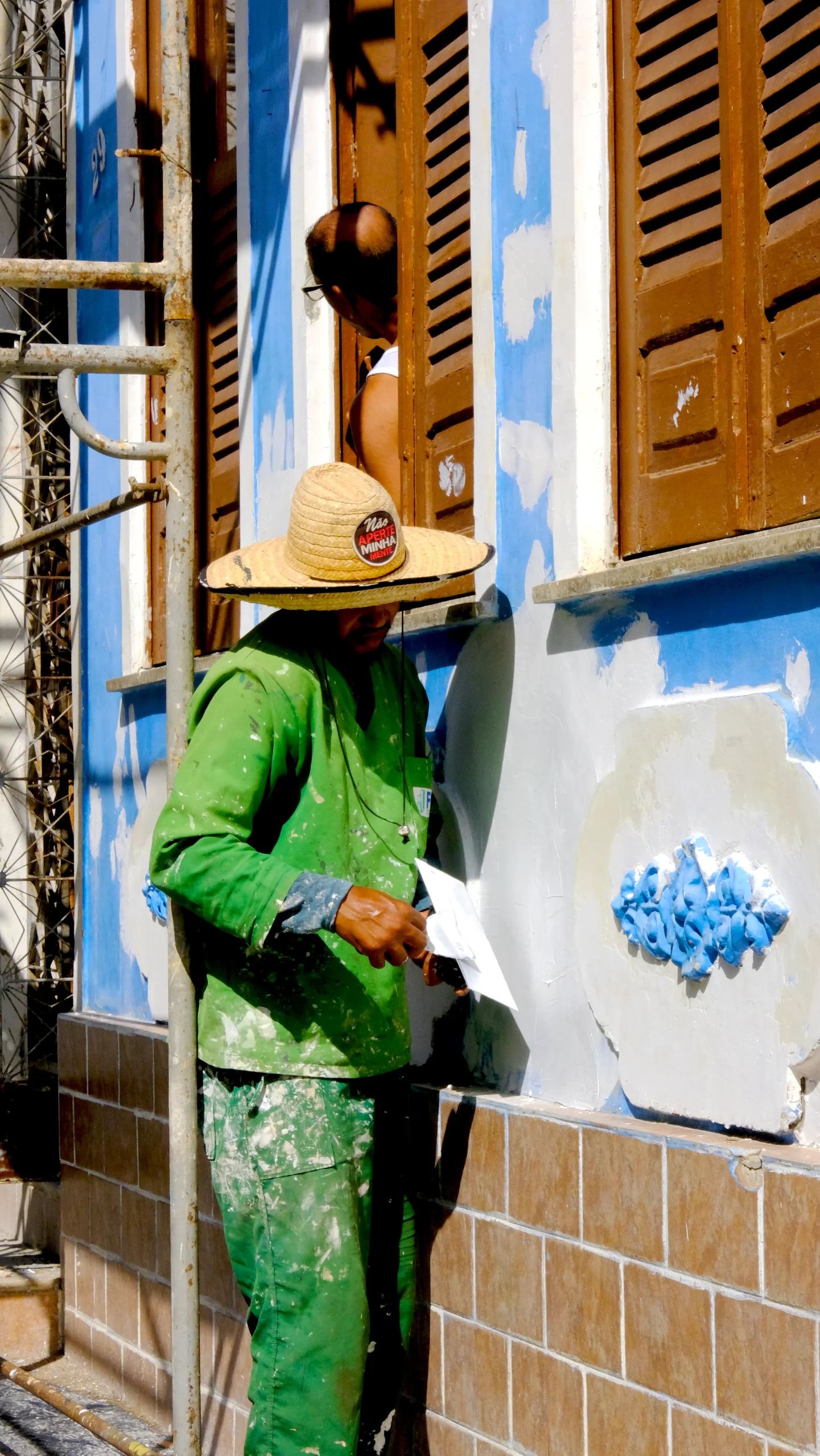 trabajador con ropa verde aplicando material en pared azul